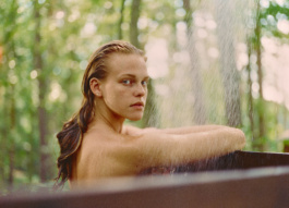 Woman in an outdoor shower glancing over her shoulder