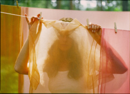 Woman's face veiled by a sheer sheet on a clothesline