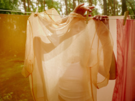 Woman peeking through a sheer orange sheet on a line