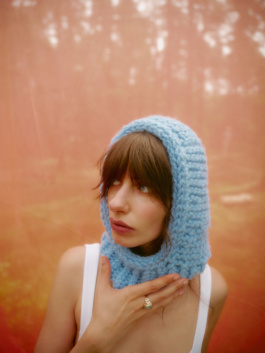 Woman in a pale blue crochet hood against orange light