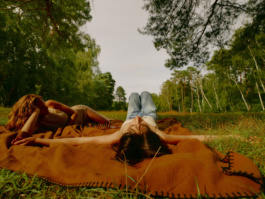 Two women lying on a blanket with arms stretched overhead