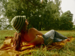 Woman lying on an orange blanket in a striped bucket hat