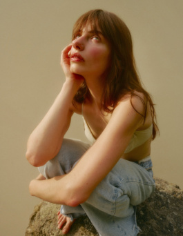 Woman sitting on a rock hugging her knees looking up