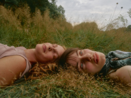 Two women lying head to head in a grass field