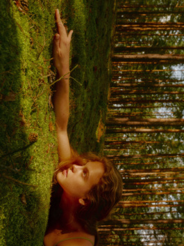 Woman reaching up to touch a mossy tree trunk