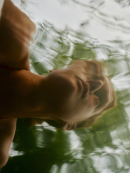 Woman floating underwater with her face breaking the surface