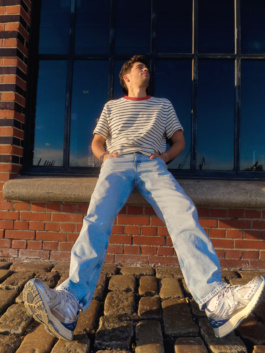 Young man leaning back on a stone ledge outdoors
